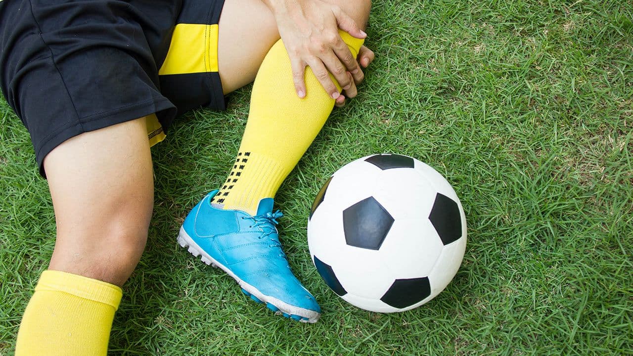 Athlete holding injured knee on sports field